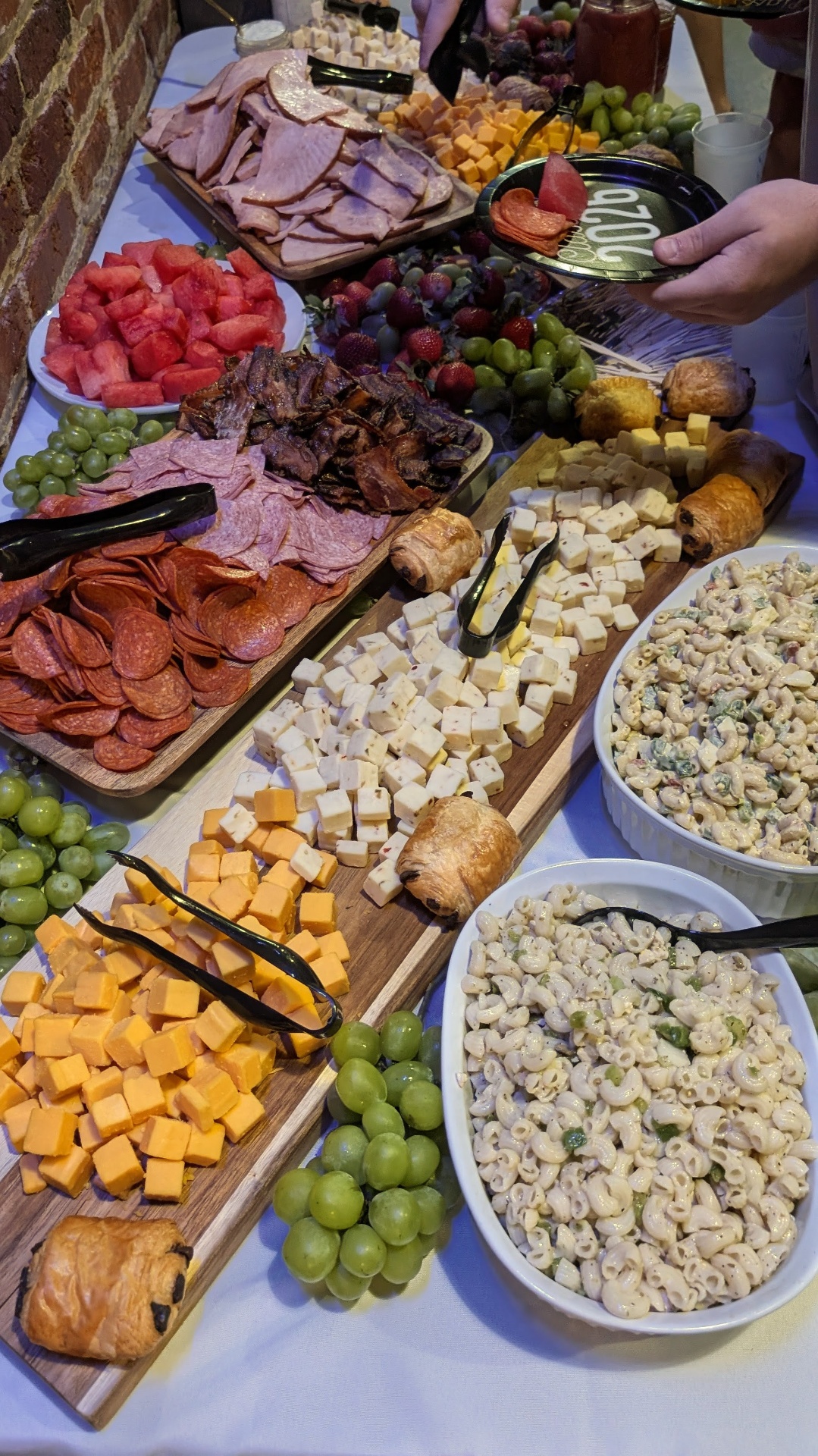 Gluten-free charcuterie board with pepperoni, salami, smoked brisket, sharp cheddar, pepper jack, fresh fruit, and chocolate croissants
