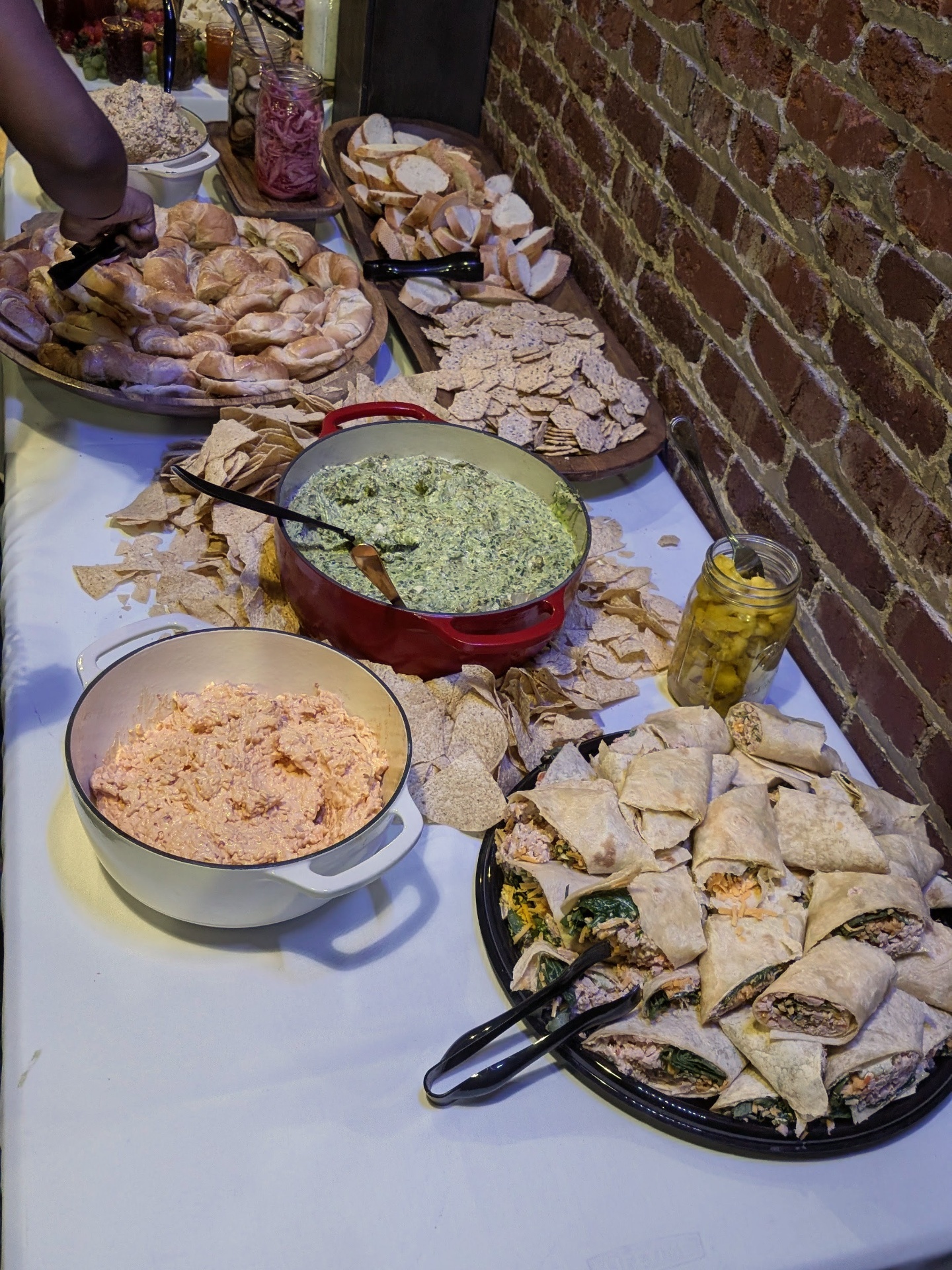Gluten-free turkey wraps, spinach artichoke dip, pimento cheese, and gluten-free croissants on a brick wall table